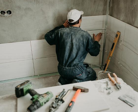 person installing a sink in a bathroom with blue tiled wall and wooden countertop 7 tips for bathroom renovation