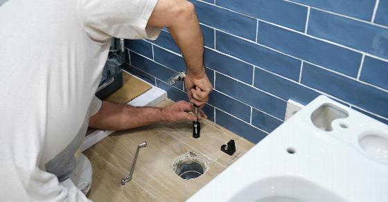 man tiling a wall with white tiles in a bathroom renovation project using a level tool showing the step by step process of home improvement